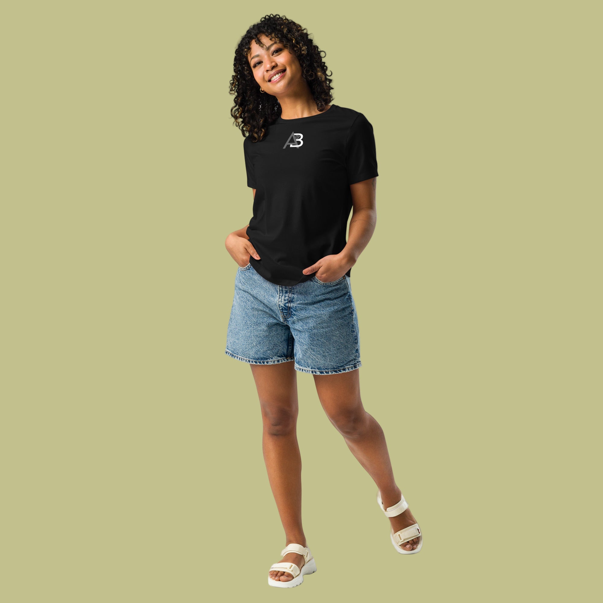 Person wearing a black t-shirt with a logo and denim shorts on a light green background