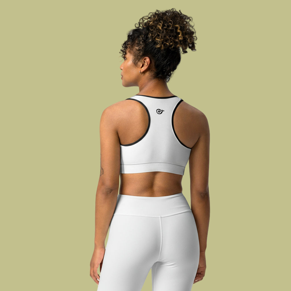 Woman wearing a white sports bra and leggings on a light green background