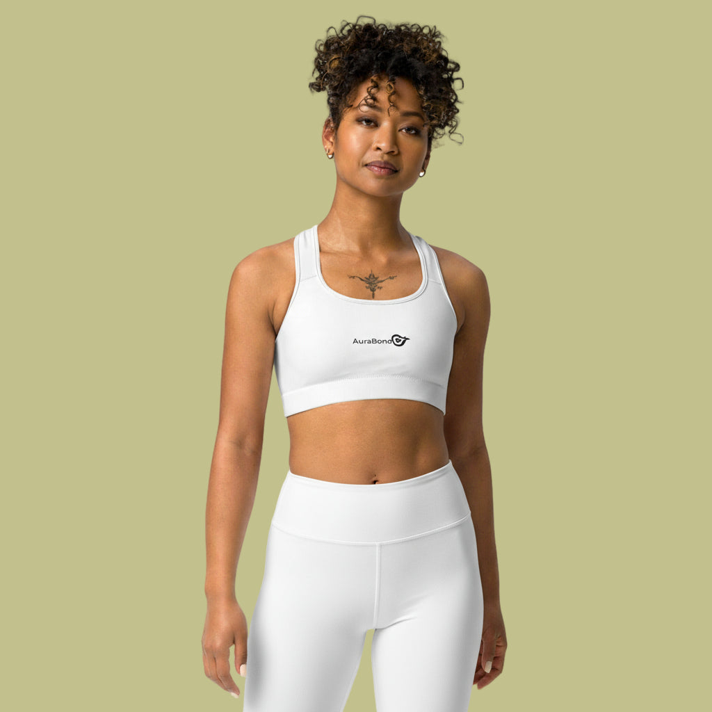 Woman wearing a white sports bra and leggings with a visible brand logo on a beige background