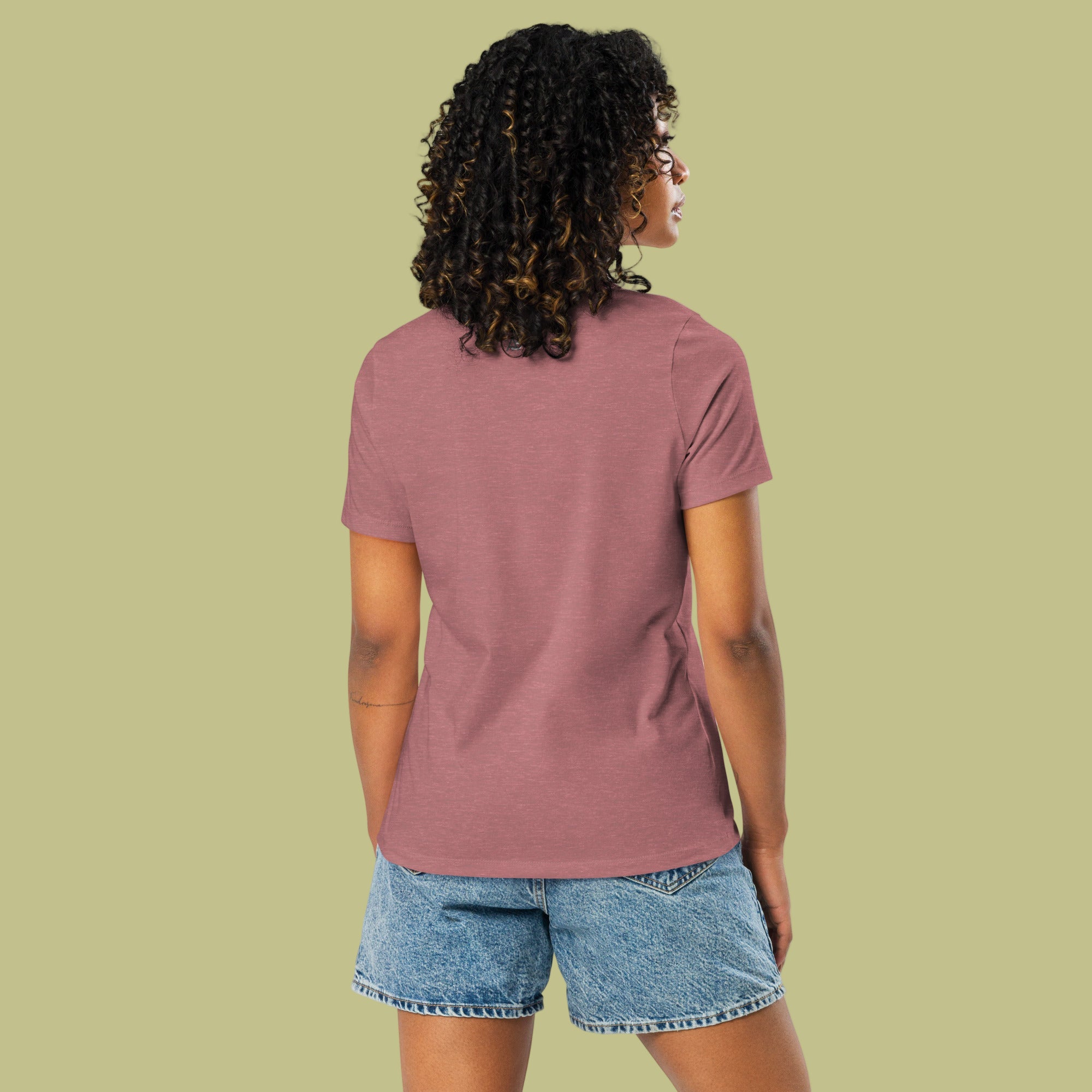 Person wearing a mauve t-shirt and denim shorts on a light green background