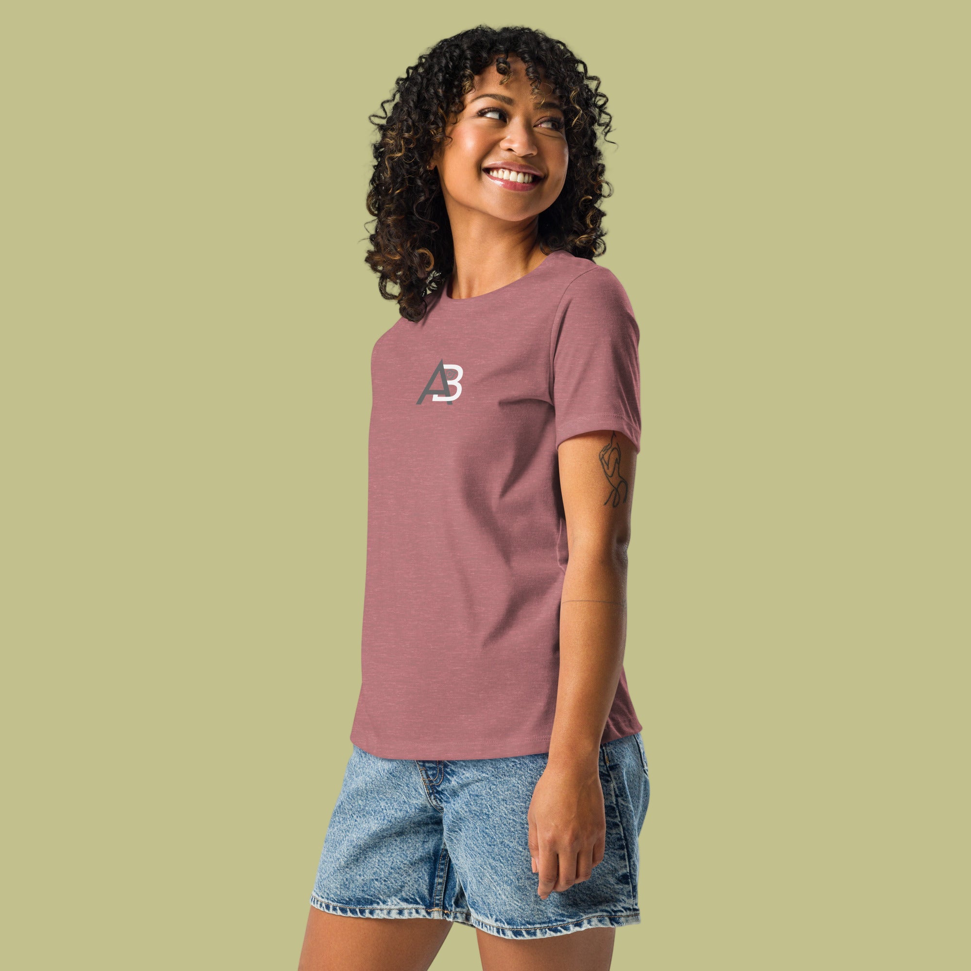 Woman wearing a maroon t-shirt with a logo and denim shorts on a white background