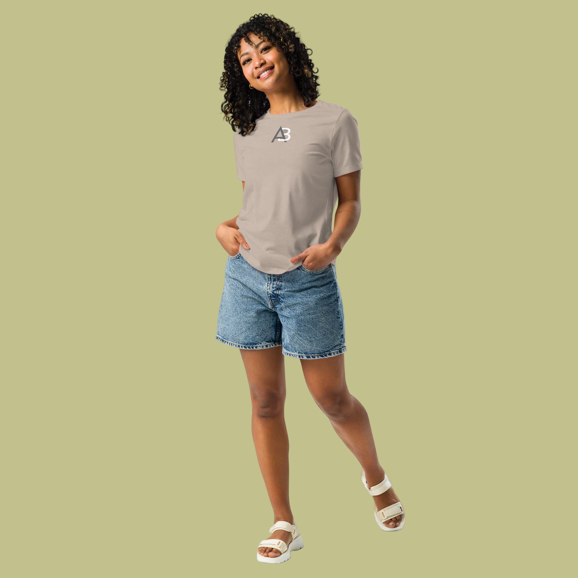 Woman wearing a beige t-shirt with a logo and denim shorts on a white background